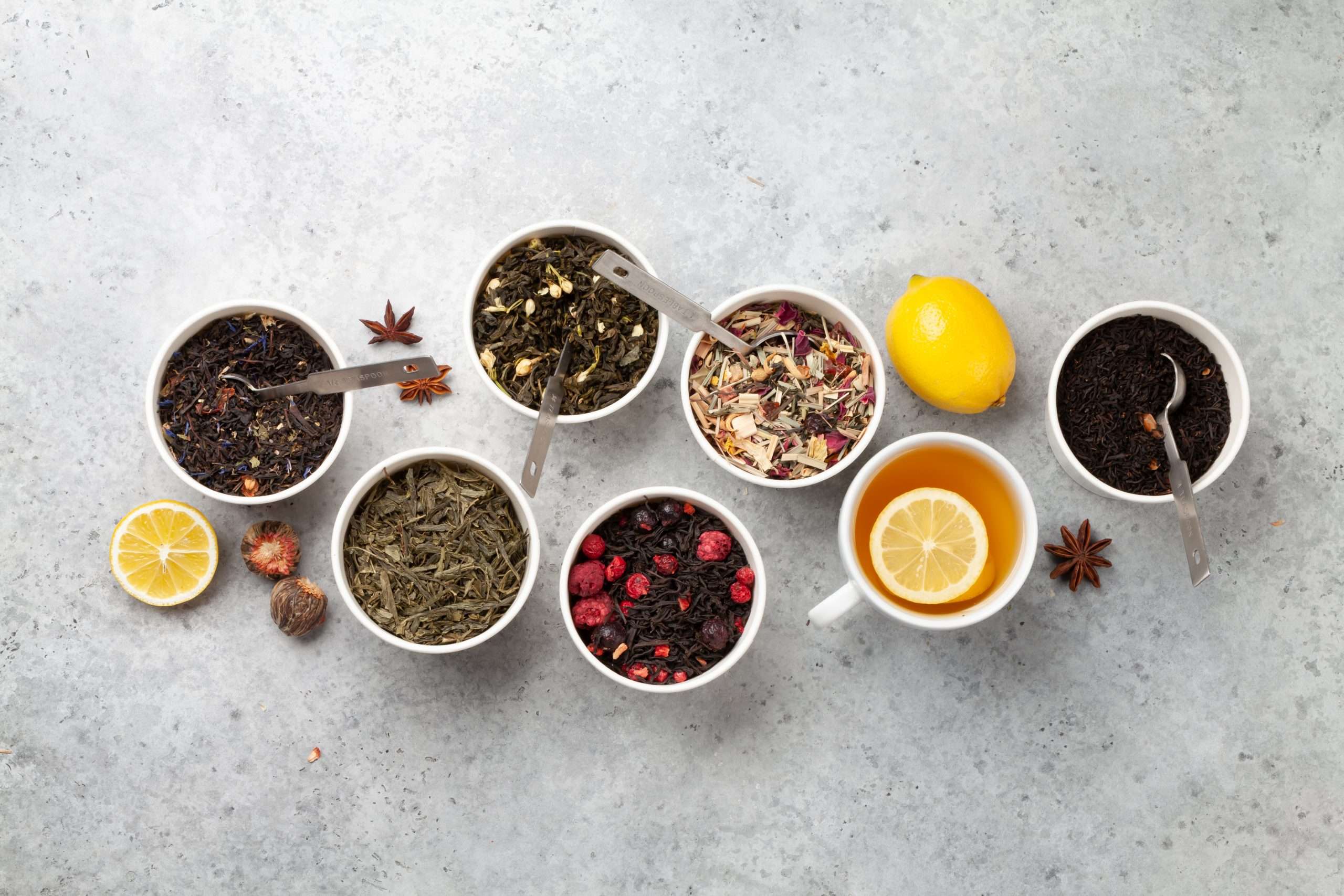 Bowls of different loose-leaf teas with lemon and star anise