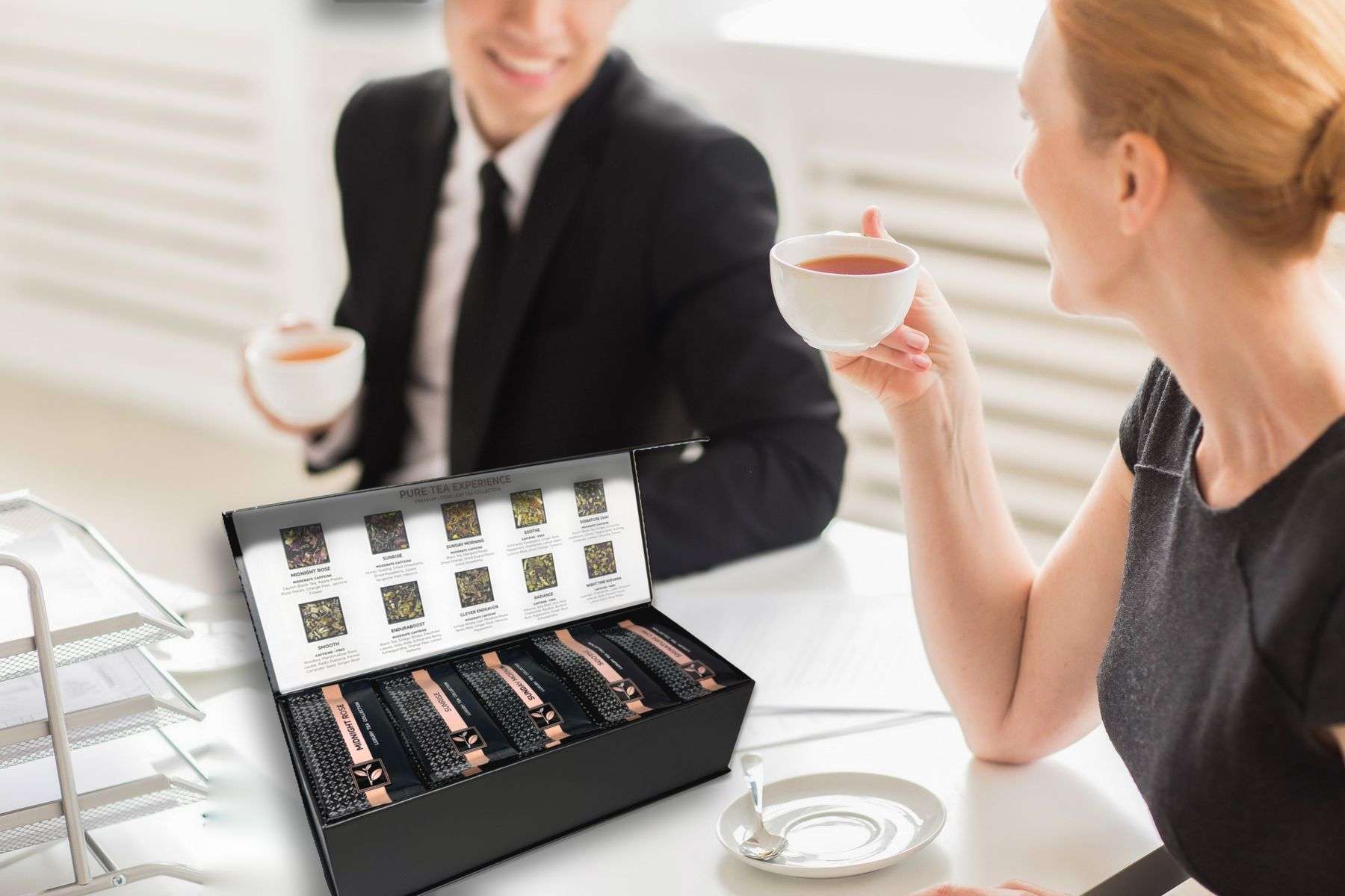 Two colleagues sharing tea at the office with the Pure Tea Experience gift box open on the table